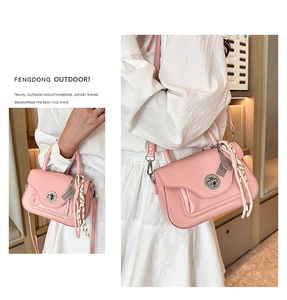 Vista dettagliata di una borsa in pelle rosa con chiusura a scatto, foulard e ciondolo in metallo