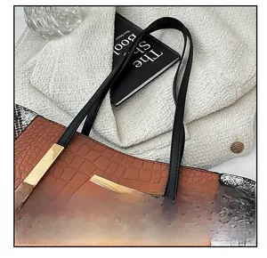 Dettaglio della borsa tote patchwork con trama coccodrillo e pitone e fibbie dorate