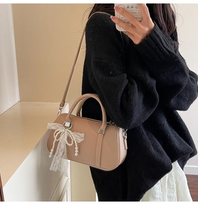 Detail of beige litchi grain Boston bag with pearl beads and lace bow decoration