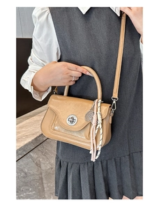 Dettaglio della borsa in pelle PU color cammello con ciondolo a racchetta e chiusura