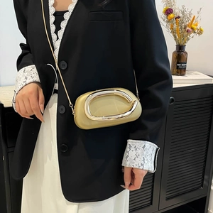 Elegant gold oval hard shell clutch with metal ring handle and slender chain strap