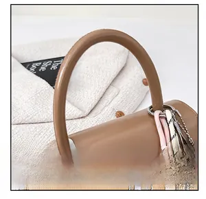 Dettaglio del manico della borsa in pelle marrone con anello d'argento e charm tennis
