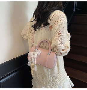 Detail of pink Boston bag featuring pearl lace bow and lychee texture leather finish