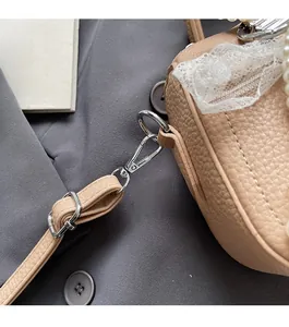 Dettaglio borsa in pelle beige con manico di perle e fiocco in pizzo decorativo