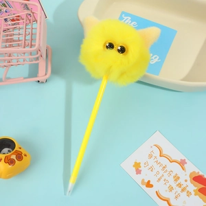 Penna a sfera a forma di volpe di peluche gialla su scrivania con decori vivaci