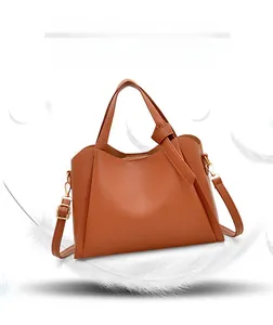Close-up of brown litchi grain leather handbag featuring knotted strap and gold hardware