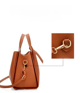 Detail of brown pebbled leather texture and detachable strap buckle on bucket bag