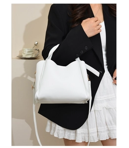 Close-up of white soft leather bucket bag with gold hardware and stylish crossbody strap