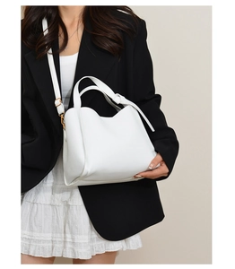 Close-up of white lychee-patterned bucket bag with gold hardware and leather shoulder strap