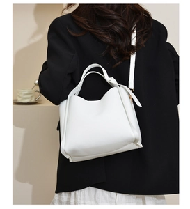 Detail of white lychee leather texture on a bucket bag with gold hardware accents