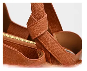 Close-up of caramel leather handbag featuring litchi grain texture and strap handle detail