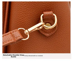 Close-up of golden metal detachable strap buckle on brown lychee grain leather handbag