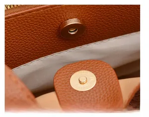 Detailed close-up of brown pebbled leather handbag with strong gold magnetic buckle closure