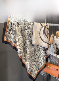 Detailed view of silk square scarf featuring black rose print and orange striped border