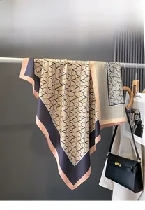 Detail of elegant silk square scarf with geometric V-pattern and navy champagne border
