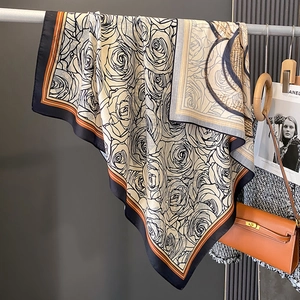 Elegant camellia print silk scarf in beige and orange, draped as a luxury fashion wrap