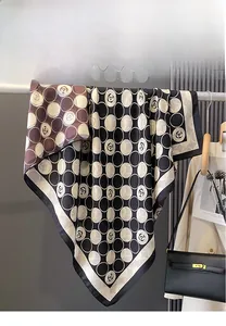 Detail of double-sided camellia polka dot silk scarf draped with a stylish handbag