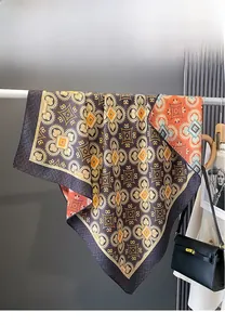 Detail of double-sided silk scarf with retro geometric patterns draped over a bag