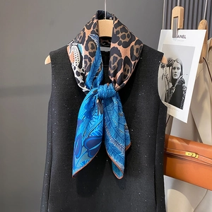 Double-sided silk scarf with leopard print and blue tropical patterns on tweed vest