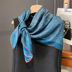 Blue H-pattern scarf with orange border and feather details on a black sequin top