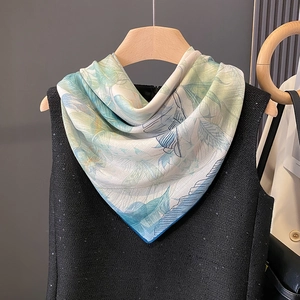 Elegant silk scarf with blue feather and leaf print on a tweed dress for a stylish look