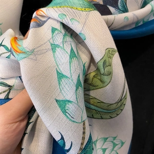 Detail of silk scarf showing herringbone texture and floral print with navy hem