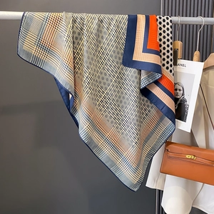 Polka dot and houndstooth scarf with orange and navy trim draped on a rack