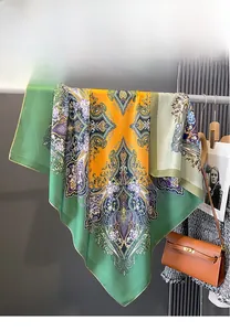 Détail d'un foulard en soie à imprimé double face aux motifs paisley vert et orange