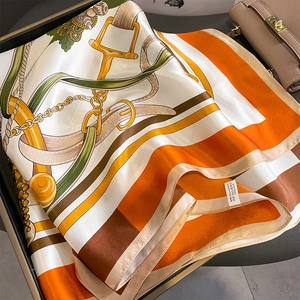 Silk square scarf featuring luxury equestrian horsebit patterns in vibrant orange and white