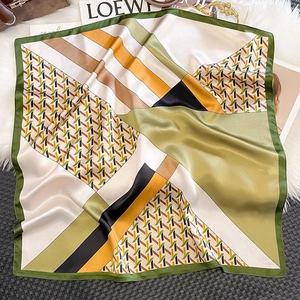 Close-up van geometrische zijden sjaal met abstracte groene en karamel patronen