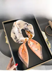 Flat lay of a mulberry silk floral square scarf tied in a bow on a black display tray