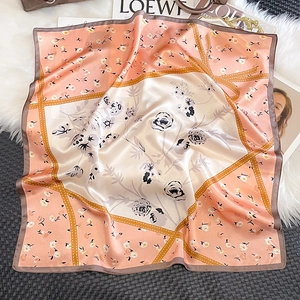 Detailed view of floral silk scarf featuring peach and cream patchwork with elegant rolled edges