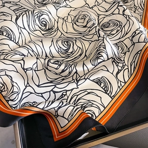 Silk square scarf featuring white and black rose prints with orange geometric borders