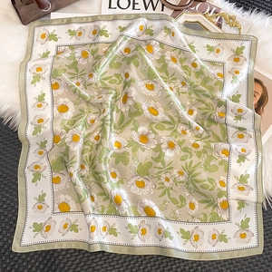 Close-up of a 100% silk floral square scarf with daisy prints on a soft white background