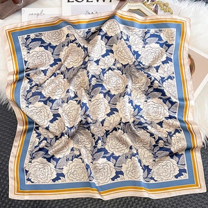 Detail of luxury silk scarf featuring cream peony floral prints and navy blue border