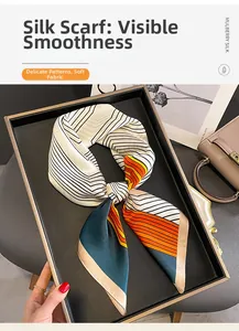 Gros plan d'un foulard en soie aux lignes géométriques orange et vert et texture de luxe