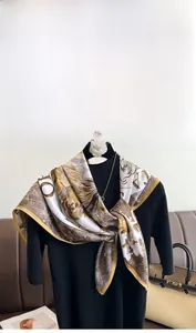 Detailed close-up of premium silk scarf with elegant gold and white monogram print