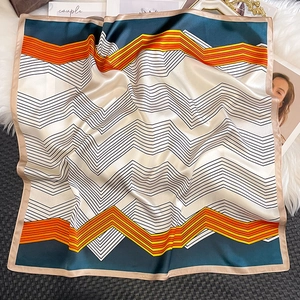 Détail d'un foulard carré en soie aux motifs de vagues colorées sur un satin brillant
