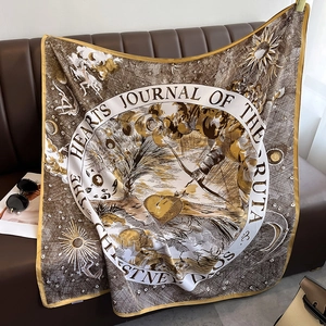Detail of luxury silk scarf with vintage sun and moon print draped on a leather sofa