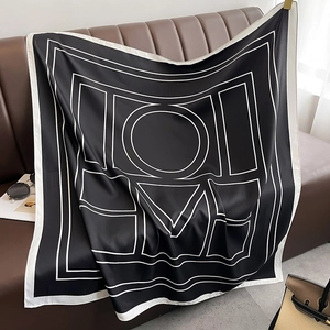 Vue détaillée d'un foulard carré en soie avec imprimé LOVE sur fond en cuir foncé