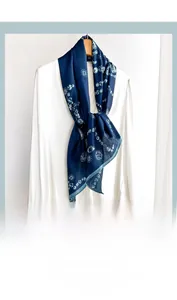 Close-up of a navy blue skinny scarf with white celestial patterns on a white shirt