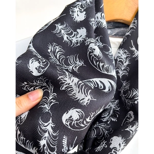 Black cotton-linen scarf with white feather print and herringbone texture on hanger