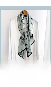 Detail of gray-blue diagonal silk scarf with ink circle patterns styled on a white shirt