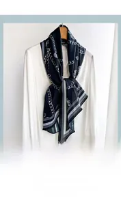 Detail of silk scarf with navy chain pattern and contrast border on a white shirt