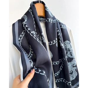 Elegant black silk scarf with chain and tiger pattern hanging on a wooden hanger