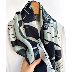 Elegant herringbone camellia skinny scarf hanging on a wooden hanger over a white shirt