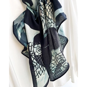 Elegant floral print scarf with artistic patterns draped on a minimalist background