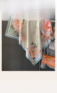 Detail of floral silk-feel scarf draped on a metal rack showing its glossy satin texture