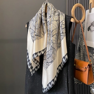 Sciarpa di seta con motivi a foglie e bordo pied de poule su un gilet nero elegante