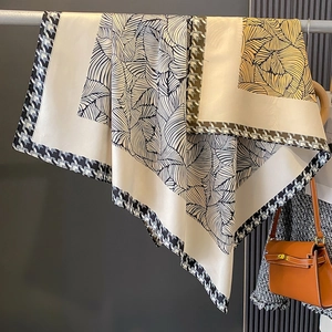 Dettaglio foulard effetto seta con bordi pied de poule e motivi di foglie eleganti